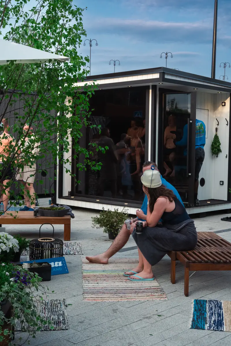 A crowd in towels and felt hats around a Contrast Crew sauna at a Finnish sauna forum