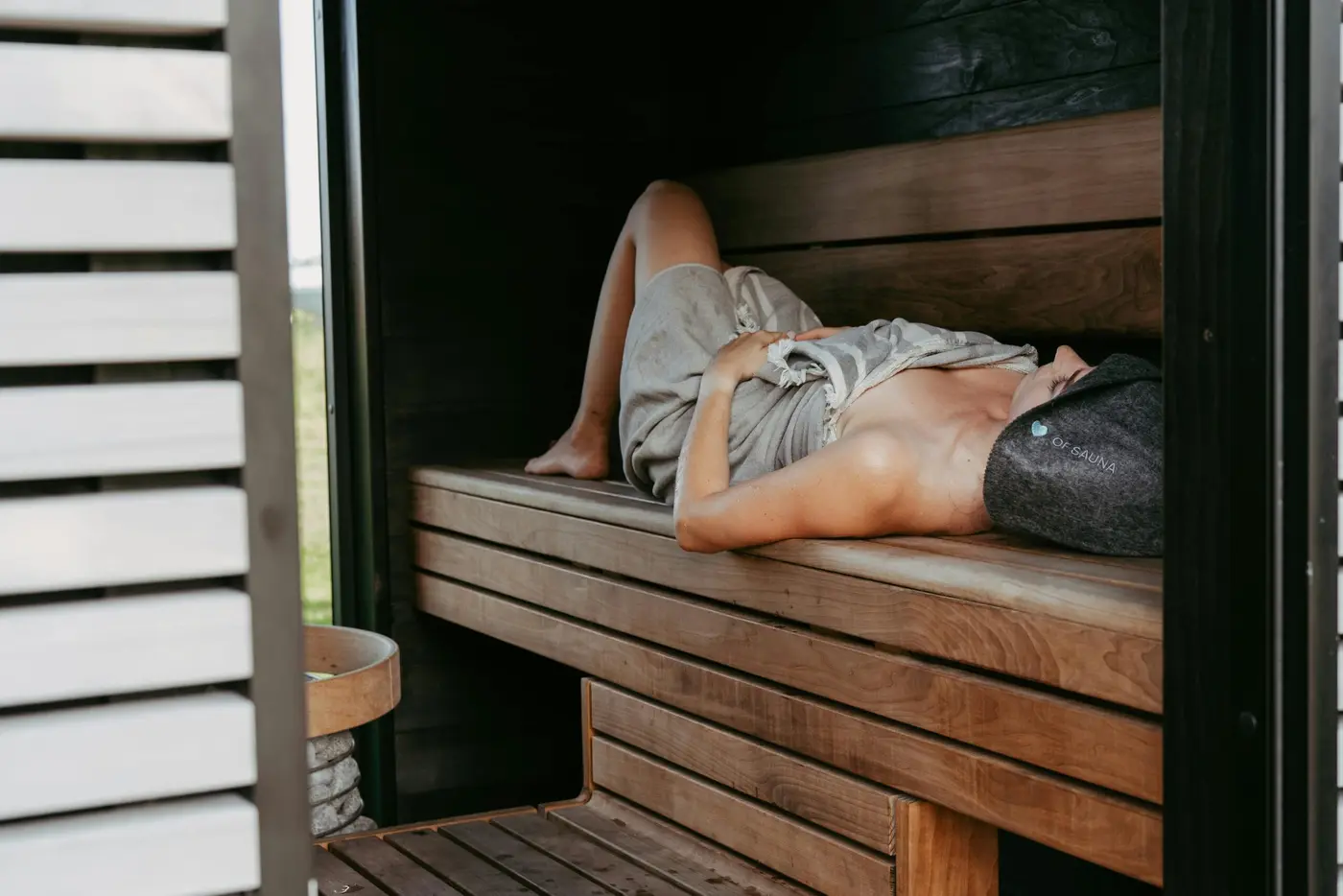 Stretched out on the cedar bench mid-session, sauna hat on, the heat settling in